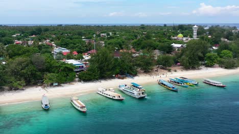 ferry-boats-docked-in-turquoise-blue-ocean-and-white-sand-beach-at-Gili-Islands