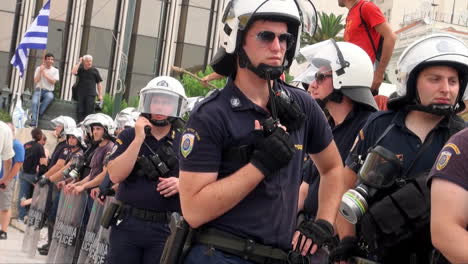 La-Policía-Antidisturbios-Griega-Con-Escudos-De-Control-De-Multitudes-Usa-Cascos-Y-Máscaras-De-Gas-Mientras-Se-Para-En-Una-Fila-Para-Formar-Un-Cordón-Durante-Un-Evento-De-Orden-Público