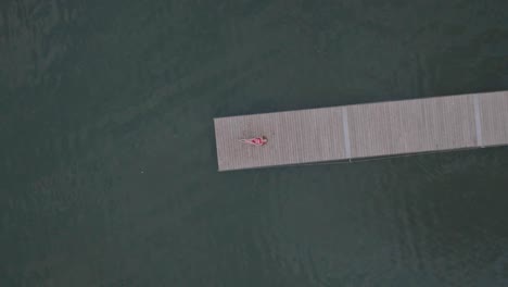 Aerial-rocket-shot-of-the-young-women-enjoying-a-summer-day-on-a-dock