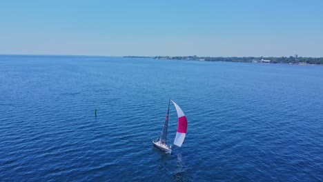 Kleines-Segelboot-Aus-Der-Luft-Im-Offenen-Wasser-An-Einem-Tag-Mit-Blauem-Himmel