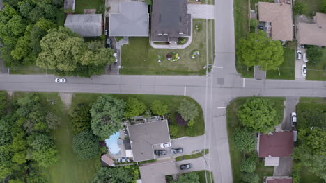 Top-down-view-of-white-car-driving-through-suburban-neighborhood