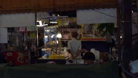 Hombre-En-Puesto-De-Comida-Por-La-Noche,-Calle-De-Bangkok