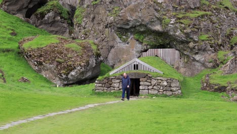 Man-walking-away-from-Stone-Hut-in-Mountain-4K