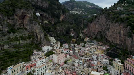 Fly-Over-Dramatic-Townscape-Of-Amalfi-Behind-Sheer-Rocky-Mountains-In-Campania,-Italy