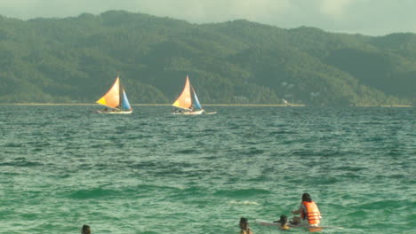 Segelboote-Rasen-Vorbei,-Während-Boracay-Touristen-Und-Einheimische-Zuschauen