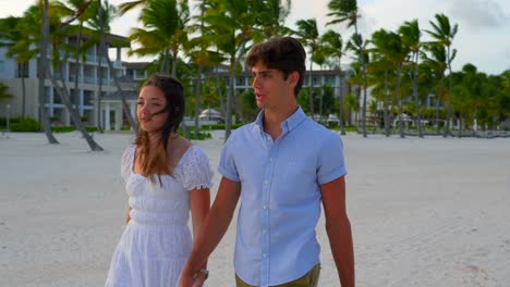 Romantic-newlywed-couple-walk-on-Caribbean-resort-sandy-white-sand-beach-at-sunset