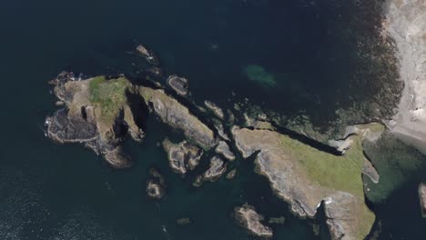Ocean-aerial-ascends-slowly-from-rugged-steep-rock-islets-near-shore