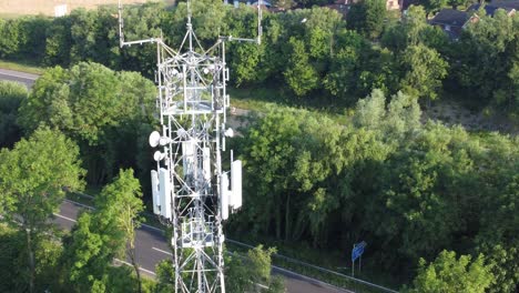 Antena-De-Torre-Celular-5g-En-El-Campo-Británico-Con-Vehículos-Que-Viajan-En-El-Fondo-De-La-Carretera-Vista-Aérea-De-La-Plataforma-Rodante-Izquierda