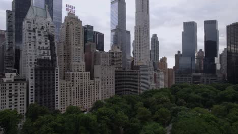 Vista-Aérea-Que-Se-Eleva-Desde-El-Parque-Central-Frente-A-Un-Edificio-Alto-En-Midtown,-Nyc,-Usa---Ascendente,-Disparo-De-Drones