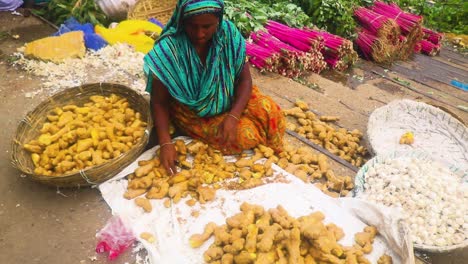 Woman-sitting-on-the-floor-at-an-Asian-street-market-selling-greens