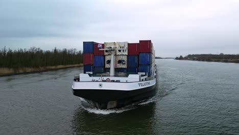 Aerial-view:-front-of-the-containership-navigating-through-the-canals-of-Zwijndrecht,-The-Netherlands