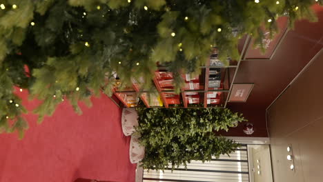 Vertical-shot-of-Christmas-trees-displayed-at-shopping-mall-store,-handheld