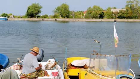 El-Hombre-Se-Sienta-En-El-Barco-Reparando-Su-Red-De-Pesca-En-El-Muelle-Del-Puerto-Deportivo-De-Sozopol