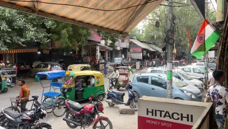 Eine-Statische-Aufnahme-Des-Chaotischen-Verkehrs-Auf-Der-Alt-Delhi-Straße,-Wo-Nur-Wenige-Autos-Und-Fahrräder-Am-Straßenrand-Geparkt-Sind