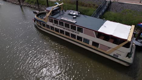 Schwimmendes-Pfannkuchenrestaurant-„All-You-Can-Eat“-Pannenkoekenboot-Vor-Anker,-Von-Oben-Gesehen-Am-Ufer-Der-Historischen-Hansestadt-Nijmegen,-Während-Es-Auf-Passagiere-In-Der-Maas-Wartet