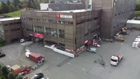 Neumann-bygg-professional-building-materials-dealer-in-Nesttun-Bergen-Norway---Aerial-overview-of-shop-with-cars-on-parking-lot-and-company-logo-on-building