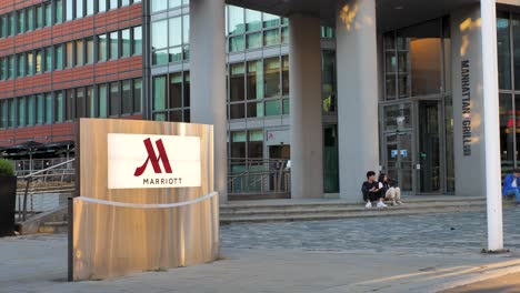 Canary-Wharf-London-United-Kingdom-July-2022-Wide-establishing-shot-of-Marriott-hotel-with-company-flag-blowing-in-the-wind