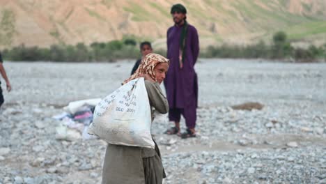 Joven-Niño-Pakistaní-Caminando-Por-Llevar-Un-Saco-Lleno-De-Ayuda-En-La-Unidad-De-Inundación-En-Una-Parte-Remota-De-Baluchistán