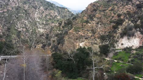 Aerial-push-in-shot-of-the-rocky-rugged-mountain-landscape-over-Eaton-Canyon-Falls-Trail-and-Chuck-Ballard-Memorial-Bridge-in-Angeles-National-Forest