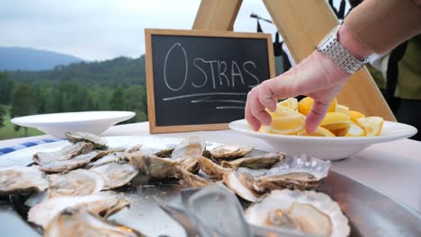 backward-movement-uncovering-hand-squeezing-a-lemon-on-top-of-oysters-at-an-event-in-Galicia