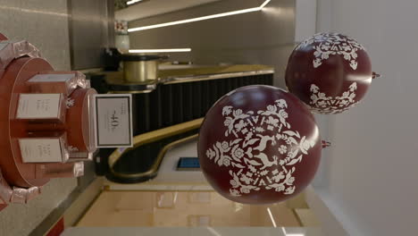 Closeup-of-red-decorated-Christmas-balls-displayed-at-shopping-mall,-circle-pan