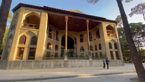 Weiter-Blick-Auf-Den-Persischen-Palast-Hasht-Behesht-Pavillon-Mit-Holzsäule-Backsteinarchitektur-Design-Menschen-Gehen-Radfahrer-Auf-Pinien-In-Der-Kulturhauptstadt-Des-Imperiums-Isfahan-Bei-Sonnenuntergang-Isfahan