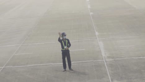 A-dedicated-airport-worker-in-uniform-waves-good-bye-to-the-pilot-while-take-off