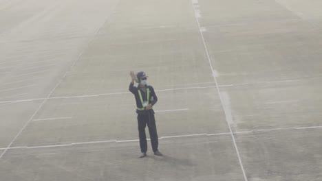 Un-Trabajador-Aeroportuario-Dedicado-En-Uniforme-Se-Despide-Del-Piloto-Mientras-Despega