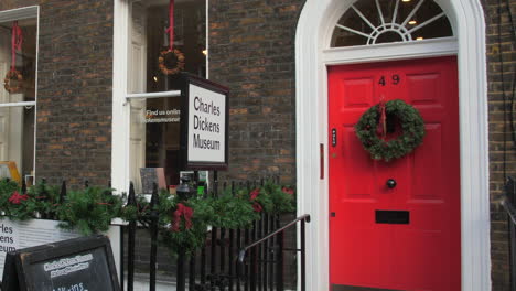 Puerta-Roja-Y-Verja-De-Hierro-Del-Museo-Charles-Dickens-Decorada-Con-Adornos-Navideños-En-Londres,-Reino-Unido