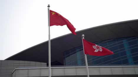 Chinesische-Und-Hongkongische-Nationalflaggen-Flattern-Im-Wind-Am-Goldenen-Bauhinia-Platz