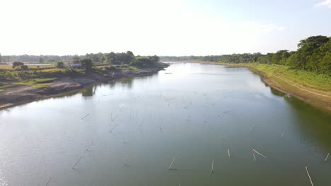 Nahflug-über-Den-Surma-Fluss-Mit-Bäumen-Auf-Der-Rechten-Seite-Des-Flusses-Und-Reisfeldern-Auf-Der-Linken-Seite-In-Sylhet,-Bangladesch