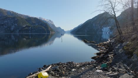 Slow-push-in-to-beautiful-shoreline,-fjord-in-Norway-littered-with-plastic-waste