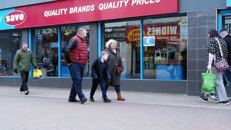 Slow-motion-shoppers-walking-in-British-high-street-shop-window-struggling-with-cost-of-living-budget-spending-crisis