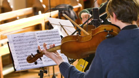 Over-the-shoulder-shot-of-a-male-violist-playing-in-a-string-quartet-in-a-small,-bright-church