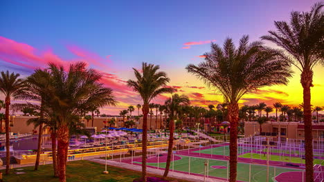 Time-lapse-shot-of-waving-palm-trees-at-hotel-resort-with-soccer-and-tennis-fields-at-sunset-in-Hurghada
