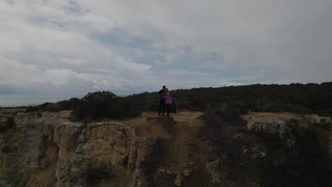 Junges-Erwachsenes-Paar,-Das-Sich-Küsst-Und-Ein-Drohnen-Social-Media-Selfie-Auf-Der-Felsigen-Küstenklippe-Von-Benagil-Macht,-Luftaufnahme,-Die-Vor-Der-Küste-Der-Algarve-Fliegt