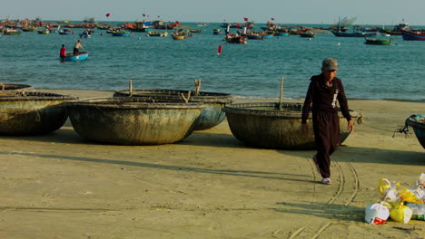 Statische-Aufnahme-Eines-Arbeiters,-Der-Sandsäcke-Neben-Kleinen-Traditionellen-Booten-In-Da-Nang-Platziert