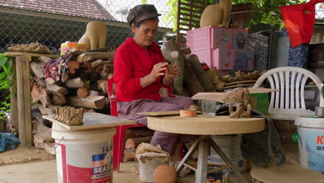 An-Asian-woman-crafts-small-animal-figures-in-clay-for-animal-shaped-flutes,-showcasing-the-souvenir-clay-tradition-of-Thanh-Ha-for-tourism