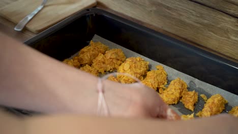 Woman-Putting-Chicken-Breast-Coated-in-Cornflakes-onto-Baking-Tray