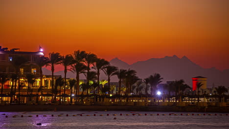 Time-lapse-shot-showing-promenade-of-Hurghada-with-palm-trees-and-mountain-silhouette-during-sunset-time