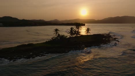 Small-tropical-island-surrounded-by-ocean-waves,-golden-hour-aerial,-sunrise