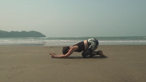 Frau-Yoga-Praxis-Am-Strand,-Erweiterte-Welpen-Asana-Position-Uttana-Shishosana