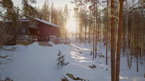 Cinematic-Shot-of-Winter-Cabin-in-Snow-Forest-and-Glowing-Morning-Sun