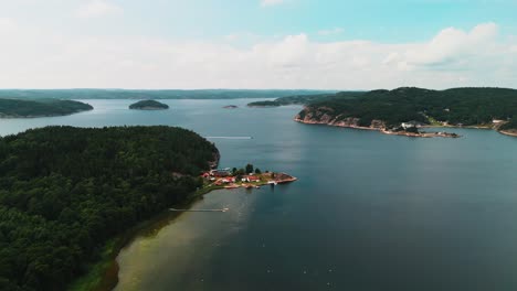 Aerial-pan-of-lake-archipelago-landscape-with-boat,-Sweden