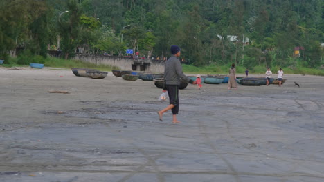Tracking-shot-of-a-local-man-walking-towards-a-boat-on-the-beach-at-Da-Nang
