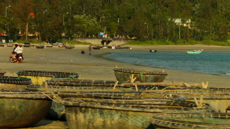 Tracking-shot-of-people-driving-along-the-beach-with-boats-on-the-shore-in-Da-Nang