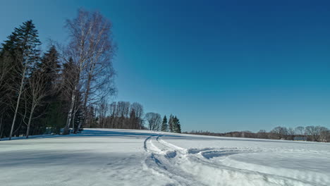 Schatten-Auf-Einem-Schneebedeckten-Feld-Mit-Spuren,-Panorama-Sonnenuntergang-Im-Zeitraffer-Mit-Blauem-Himmel