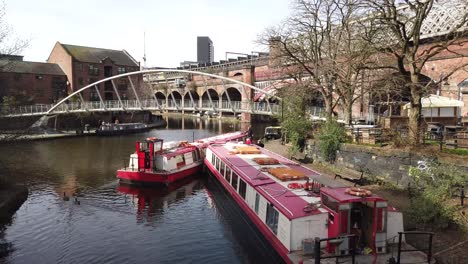 Manchester-Castlefields-canal-basin-located-near-the-Deansgate-area-of-Manchester,-UK-and-showing-modern-against-old-architecture-as-well-as-traditional-barges-on-the-canal-quayside