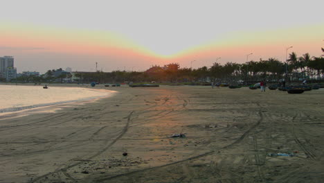 Statische-Aufnahme-Von-Menschen,-Die-An-Einem-Strand-In-Da-Nang-Entlang-Spazieren-Und-Einen-Atemberaubenden-Sonnenuntergang-Genießen