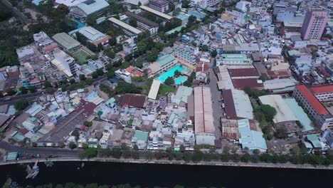 Ho-Chi-Minh-City,-Vietnam,-aerial-view-on-a-sunny-day-featuring-the-canal-green-space-and-rooftops-of-densely-populated-crowded-residential-area-and-communal-buildings